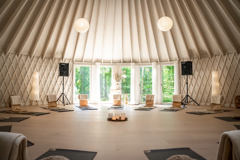 Jurtens indre med yogamåtter i cirkel og papirlamper under det ribbede loft