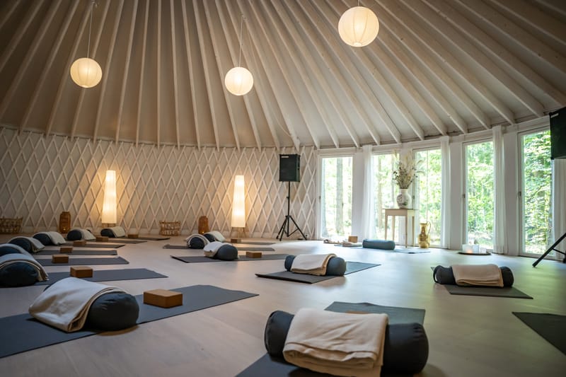 Jurtens sal med yogamåtter, bolstre og papirlamper under det hvide tag