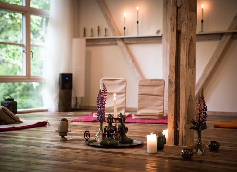 Yogasalen med tændte stearinlys, lupiner og morgenlys