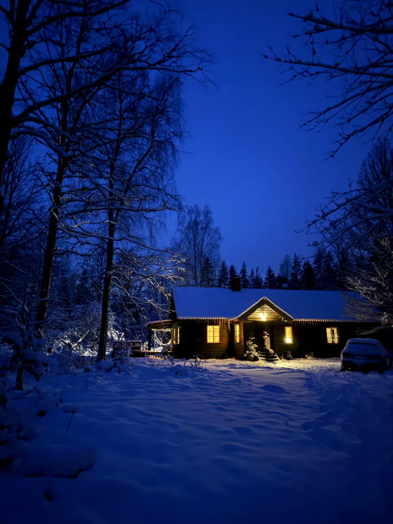 Hovedhuset med lys i vinduerne en blå vinteraften i sneen